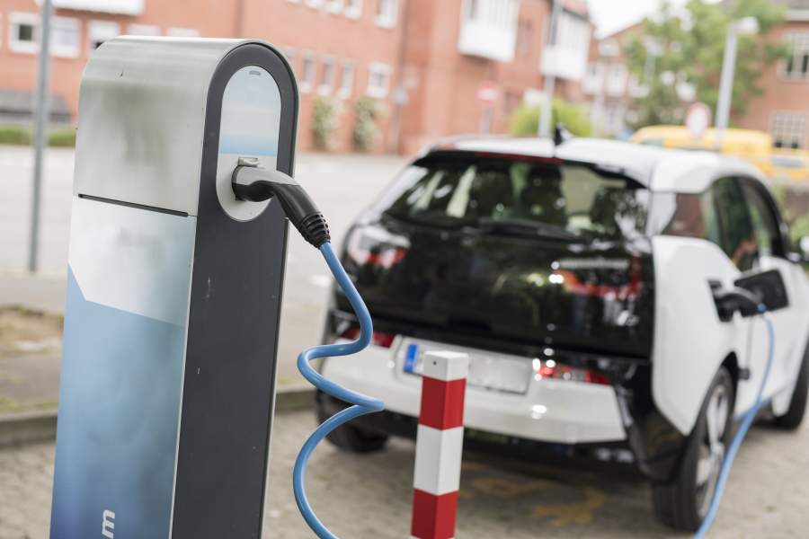 Ein schwarz-weißes Auto steht einer Ladestation und wird mit Strom betankt.