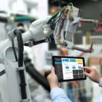 Mitarbeiter steuert einen intelligenten Industrieroboter über ein Tablet.
