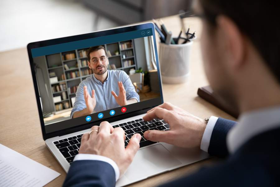 Virtuelles Business-Meeting zwischen zwei Geschäftsmännern, ein Mann im Homeoffice ist auf dem Laptop-Screen