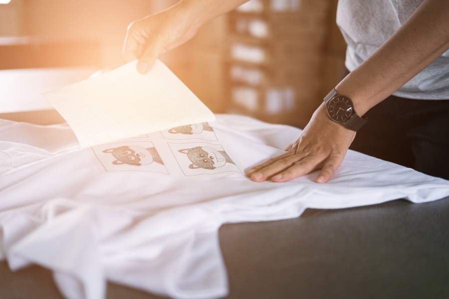 Junge Frau bringt einen Cartoon-Textildruck auf ein T-Shirt auf