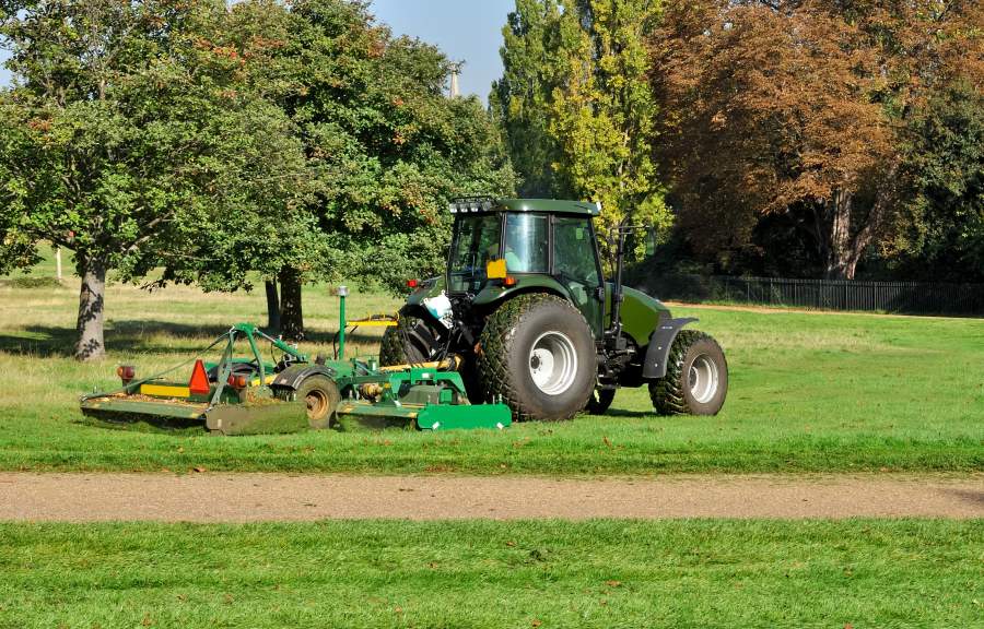 Traktor bei Pflegearbeiten auf Grünanlage, Mähen von Gras