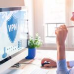 Frau arbeitet an einem Schreibtisch mit Working Station und Monitor, auf dem Bildschirm: Verbindung mit einer VPN-Anwendung für besseren Datenschutz
