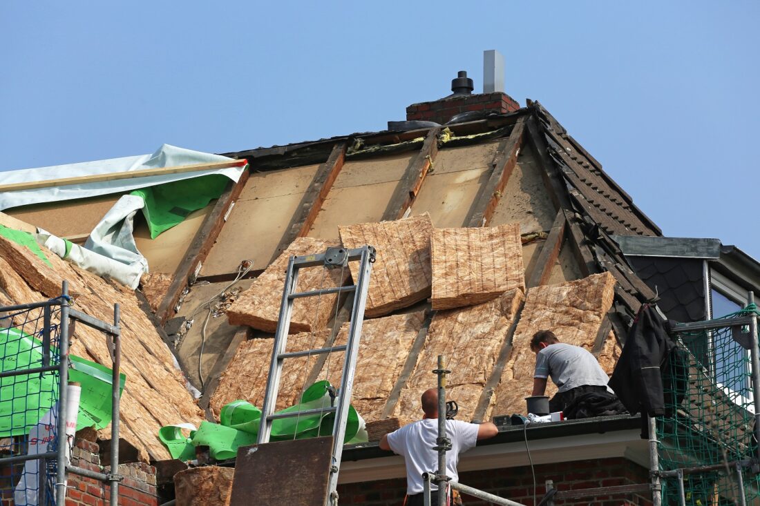 Im Zuge einer energetischen sanierung bringen arbeiter waermedaemmung auf dem dach an