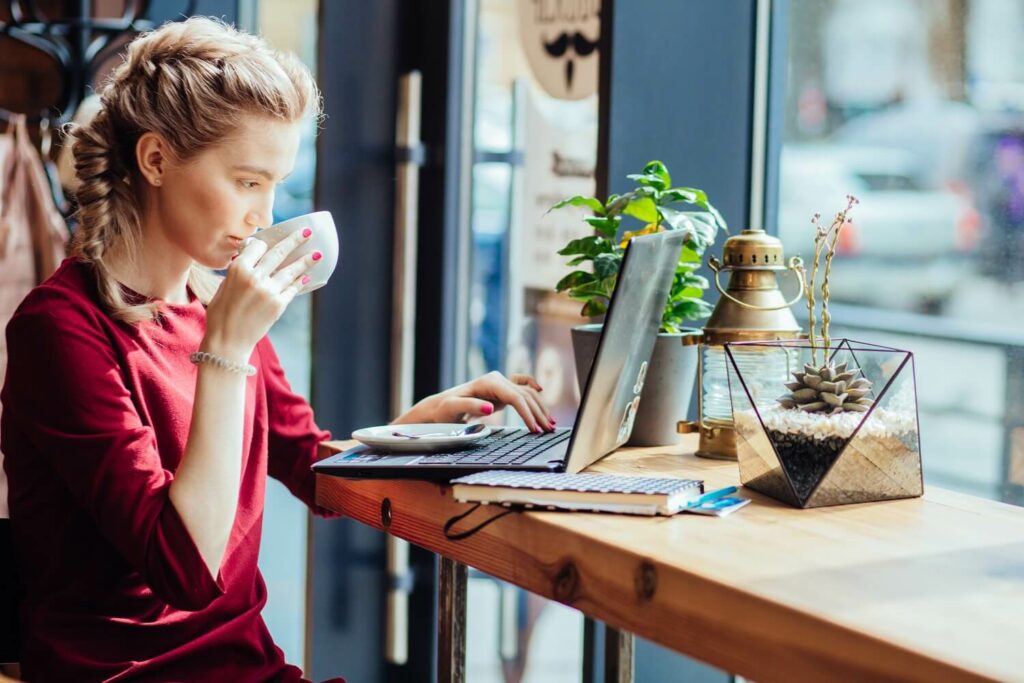 Bloggerin sitzt mit ihrem Laptop im Café und denkt nach