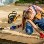 Frau ist als Hobby-Handwerker im Garten aktiv und baut eine Holzterrasse