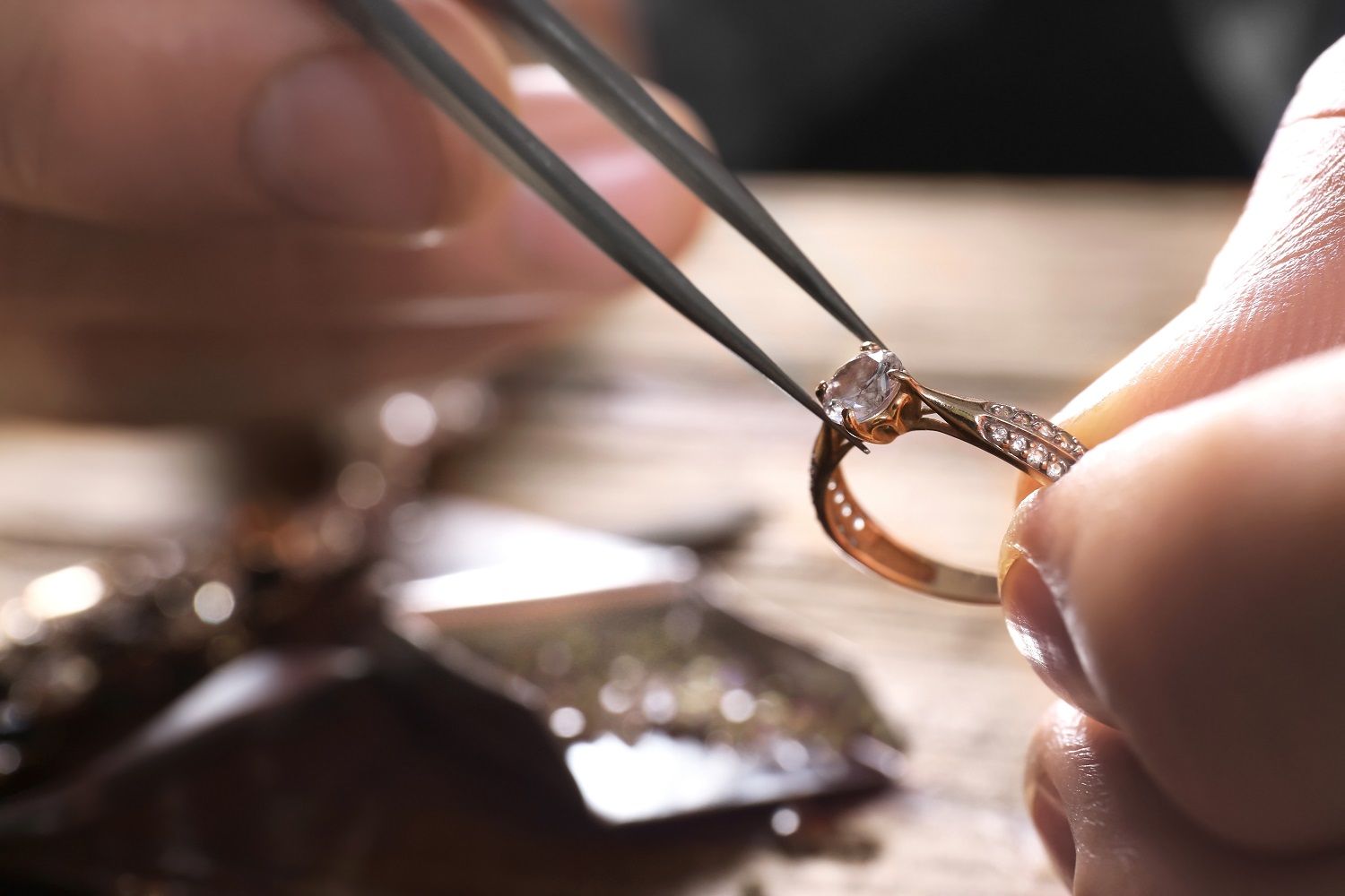 Goldschmied begutachtet Ring aus Gold mit Diamantenbesatz Close-up