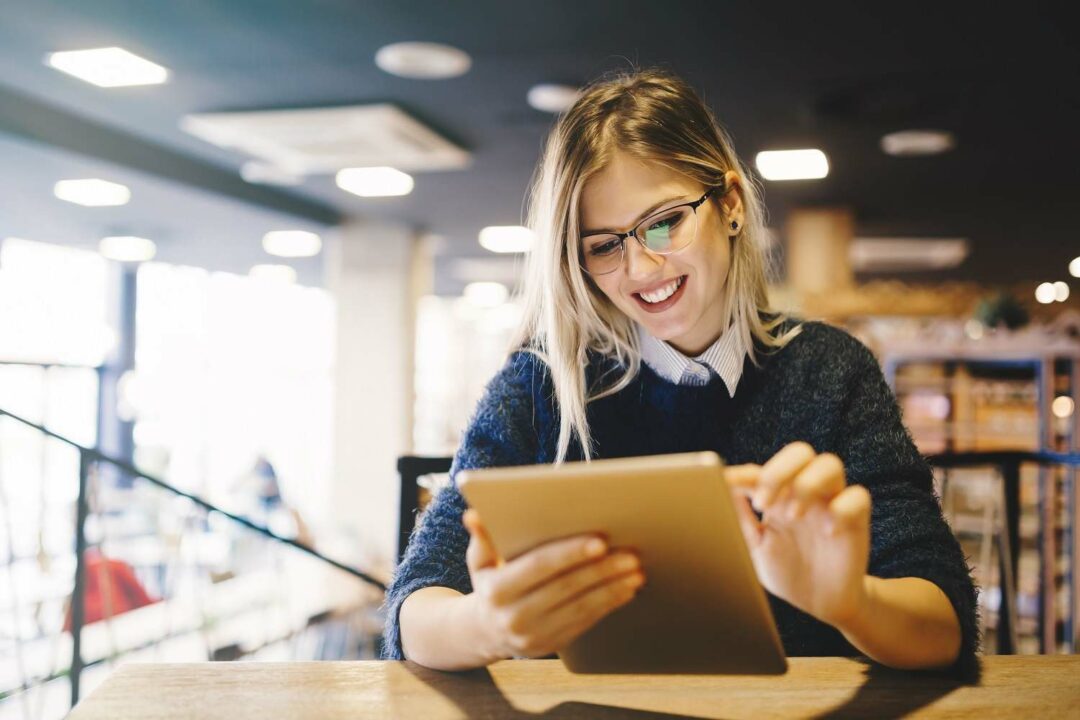 Studentin in Bibliothek schaut auf ihr Tablet