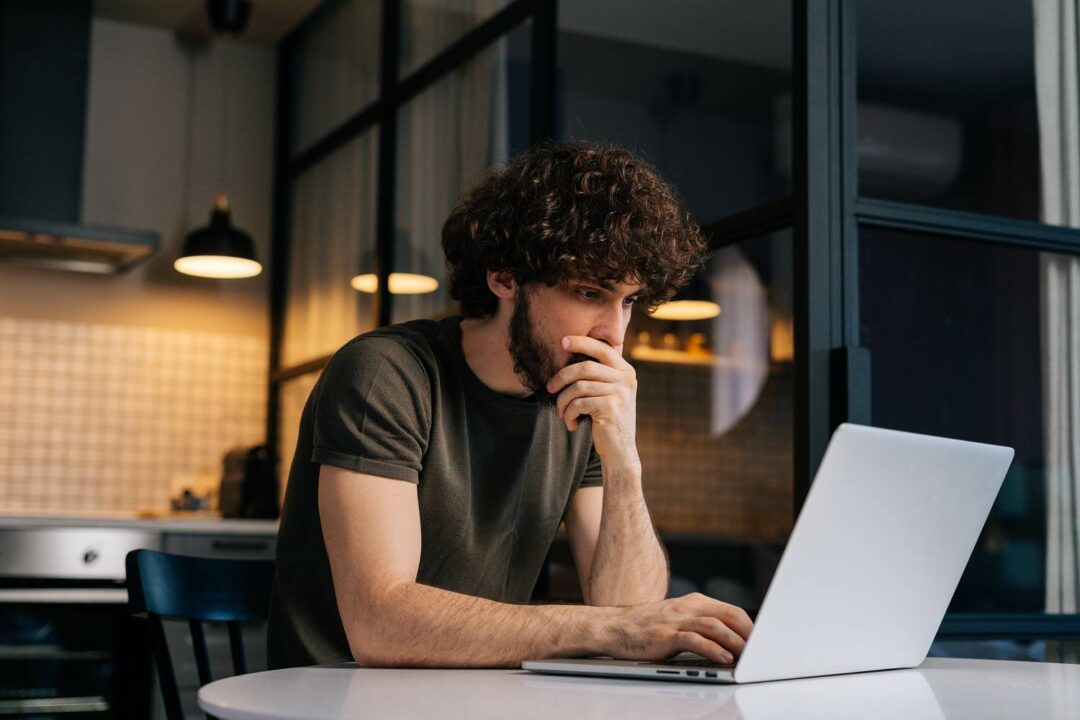 Junger Webdesigner Freelancer spät abends bei der Arbeit vor dem Laptop