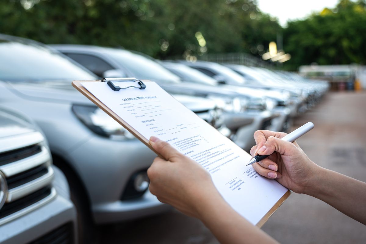 Mitarbeiter einer Autovermietung vor Autos