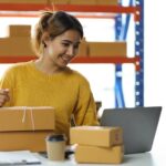 Frau verpackt gut gelaunt Waren, die sie bei Amazon verkaufen konnte