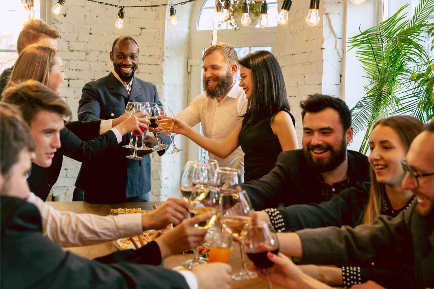 Junge Mitarbeiter einer Firma feiern gemeinsam im Restaurant bei einem Firmenevent