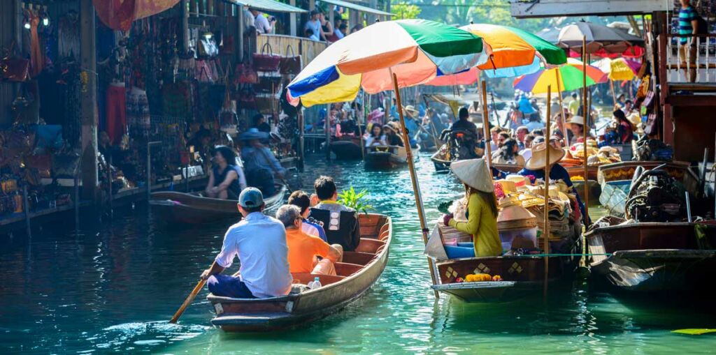 Touristen besuchen den Damnoen Saduak Floating Market mit dem Boot